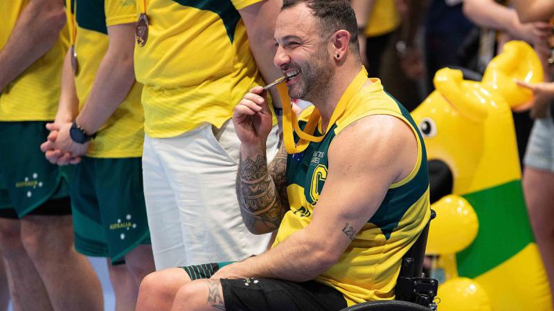 Lenny Redrose bites down on a bronze medal