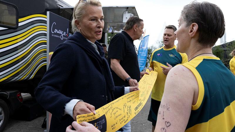 Invictus Games Team Australia competitors Mark Armstrong, rear, and Danielle Hale, front, receive a special gift from Kirsten Gerberding and Mike Hartley, members of the Courage! Die Gerberding Stiftung organisation. 