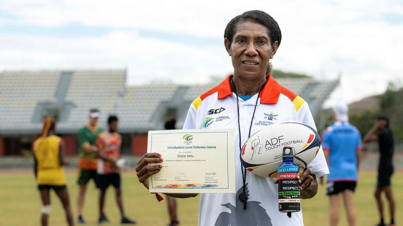Diane Vetu holding her certificate of completion of the Federation of International Touch Introductory Level Referees Course.
