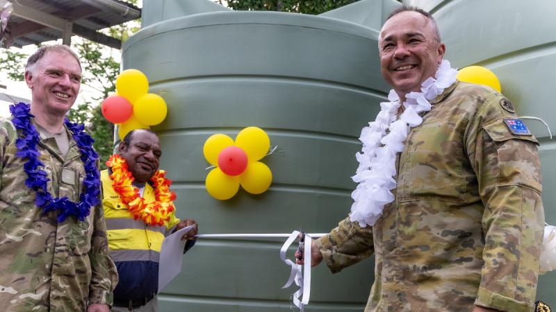 Lieutenant Colonel Glenn Mackenzie (right), Commanding Officer of Operation Lilia, cuts the ribbon on water tanks delivered through an ADF-led community infrastructure project at a handover event in the Gilbert Camp community.