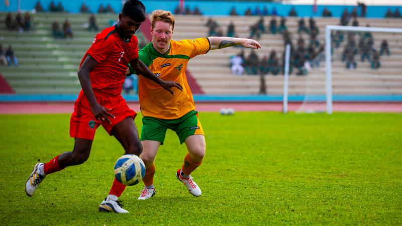 A player from Australian Defence and the Bangladesh Army football team on the field.