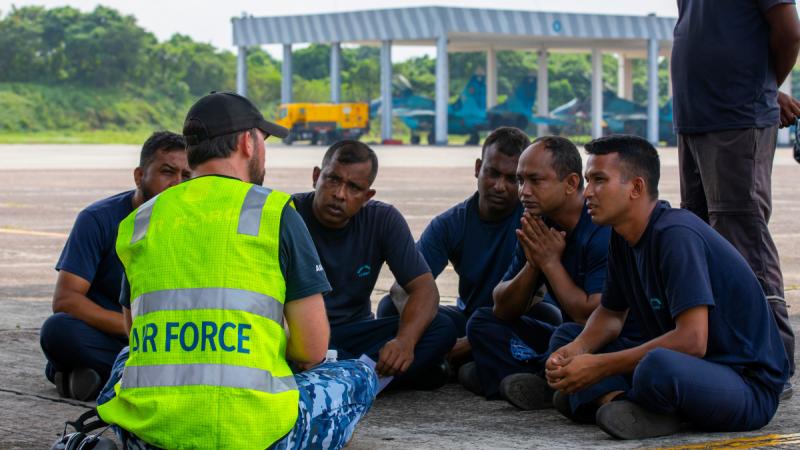 A Royal Australian Air Force member walks through RAAF C-130J Hercules components with members of the Bangladesh Air Force during Indo-Pacific Endeavour at the Bangladesh Airforce Base, Dhaka.