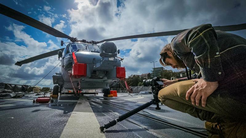 Training Force Multimedia Unit technical multimedia specialist Chris Paraskevas films an MH-60R Seahawk aboard a Canberra Class Landing Helicopter Dock.