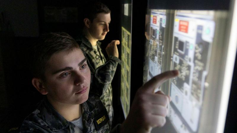  Information specialist Seaman Kyle Bergan (left) and communications specialist Seaman Alex Meiklejohn (background) conduct a fault finding exercise in the Communication Centre Simulator. 