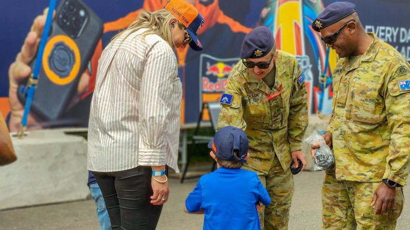 Australian Army soldiers Lance Corporal Ashleigh Jackson, centre, and Private Lib Savrimuthu, right, interact with a family at the MotoGP 2023, Phillip Island.