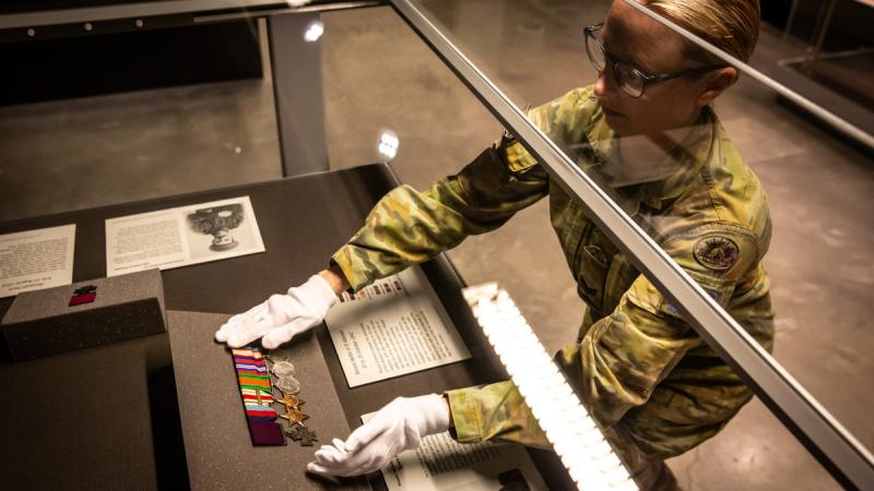 Australian Army soldier Corporal Stacey Kitcher from Army History Unit places a Victoria Cross and medal set into the display case at the Australian Army Infantry Museum, Singleton.