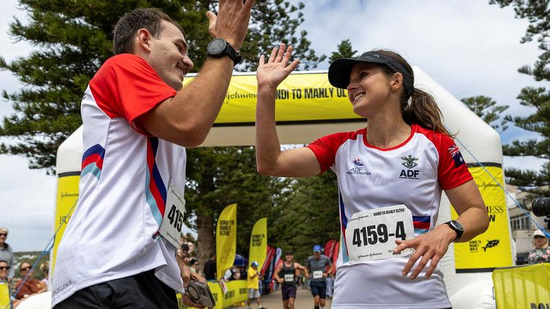 Australian Army Sergeant Amanda Robbie gives Private Andrew Lenartowicz a high five on the finish line of the Bondi to Manly Ultra in Sydney.