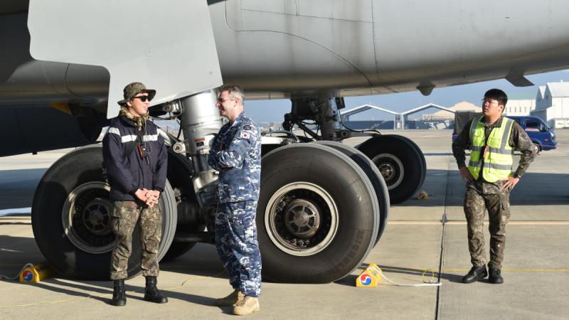 Leading Aircraftman Zachary Delaney (second from left), a  RAAF linguist speaks to a Republic of Korea Air Force member on the flightline at Gimhae Air Base, in the Republic of Korea.