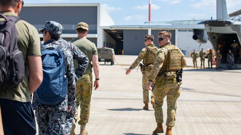 Personnel from 2 Security Forces Squadron walking on the tarmac to board a plane.