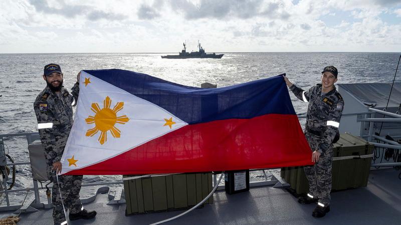 HMAS Toowoomba sailors Petty Officer Peter Sutton, left, and Able Seaman Finn Jackson display the national flag of the Philippines during the inaugural maritime cooperative activity during a regional presence deployment.