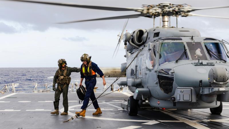 Aircrewman Leading Seaman Matthew Parry escorts Mr Liam Glackin from HMAS Brisbane’s embarked MH-60R helicopter while conducting an evacuation from Willis Island off the coast of Queensland.