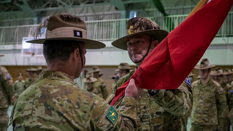 Major General Scott Winter passes on the Headquarter 1st (Australian) Division's Commander's pennant to incoming Commander Major General Ash Collingburn. 