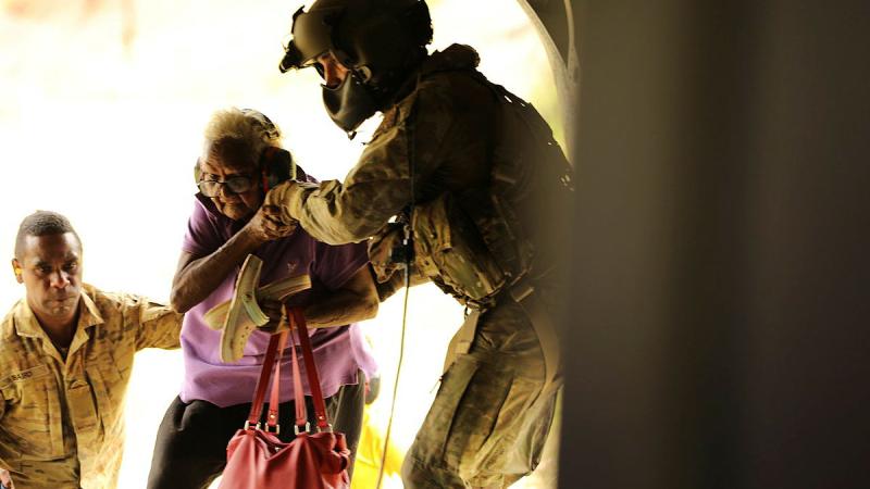 Soldiers from 51st Battalion, Far North Queensland Regiment, and 5th Aviation Regiment assist a resident to evacuate from Wujal Wujal, North Queensland. Photo: Carolyn Barnett