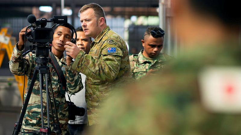 Sergeant Raymond Vance from the 1st Joint Public Affairs Unit observes a photographer from the Timor-Leste Defence Force. 