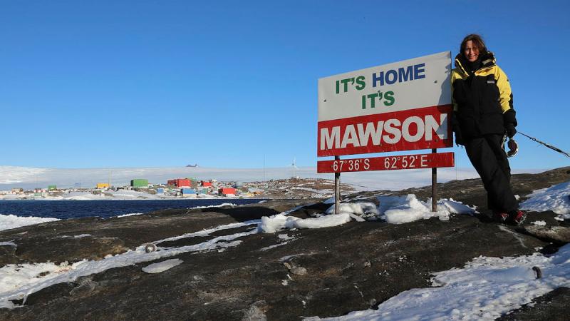 Squadron Leader Catherine Humphries with the "It's Home It's Mawson" sign at the research station. 