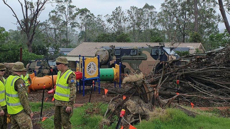 Soldiers at the Oxenford State School work to remove trees which fell during storms. 