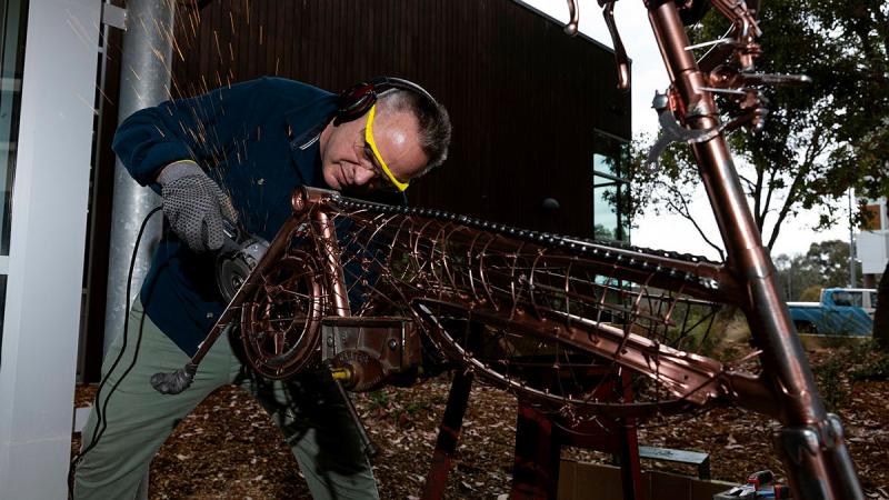  Lieutenant Commander Will Singer, works on his repurposed bicycle sculpture as part of the ADF ARRTS program at the University of Canberra's Inspire Centre. 
