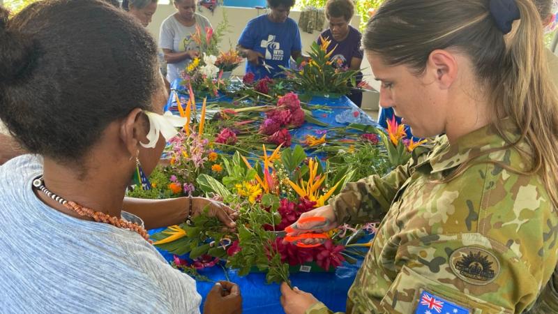 Corporal Chloe Callaghan creates a floral arrangement with eight of the Solomon Island Dominican Sisters as part of a women's event, designed to empower women in the Solomon Islands, 2024