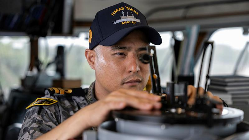  Royal Australian Navy Maritime Warfare Officer, Lieutenant Yoon Lee takes a bearing on the bridge of HMAS Yarra.