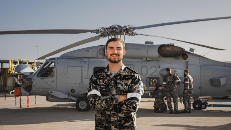 Leading Seaman Isaac Hayes an Aviation Technician from 808 Squadron in front of a MH-60R Romeo Seahawk aircraft at HMAS Albatross in Nowra, New South Wales.