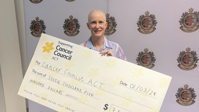Narelle Powers after having her head shaved at Reserve and Cadet Support Headquarters, holding a cheque for $7500. Photo: Emily Egan