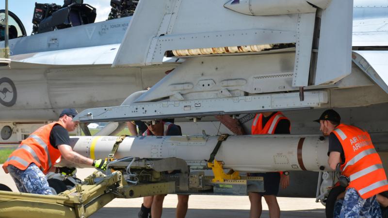 Armament technicians from 1 Squadron load an AGM-84 Harpoon anti-ship missile onto an F/A-18F Super Hornet at RAAF Base Amberley.