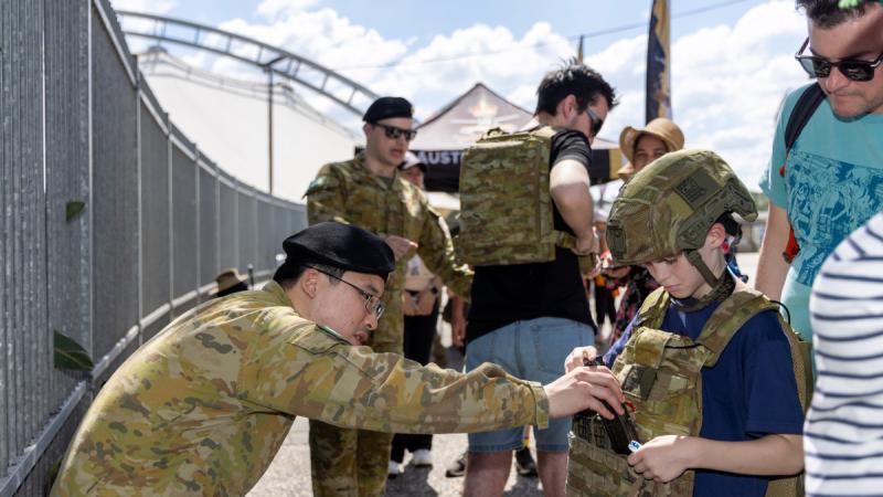 Australian Army soldier Private Peter Kim of 1/15 Royal New South Wales Lancers shows a child body armour at the Sydney Royal Easter Show.
