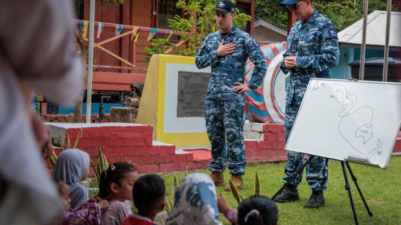 Commanding Officer 19 Squadron, Wing Commander Belinda Edmunds (r) and Flight Lieutenant Matthew Schmidt, a pilot from 6 Squadron, discuss the crash of F-111G A8-291 with local school children, Pulau Aur, Malaysia.