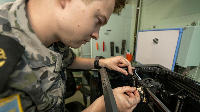 Leading Seaman Electronics Technician Nicholas Parks conducts maintenance on a 3D printer on board HMAS Warramunga while at sea. 