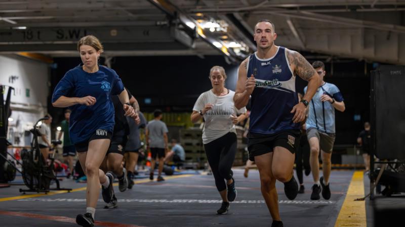 Navy personnel run during a group exercise class aboard HMAS Adelaide.