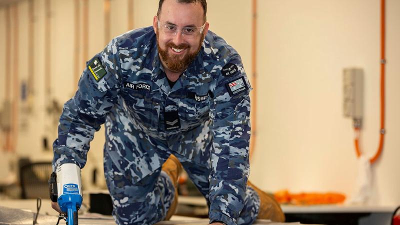 Corporal Troy Russell, an aircraft safety equipment maintainer from 11 Squadron, uses a new template to cut a piece of carpet for installation in a P-8A Poseidon. 
