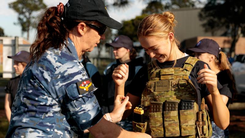 Squadron Leader Catherine Humphries (left) fits body armour to a participant in the Air Force Women in Aviation Program during a presentation by No. 26 Squadron Military Working Dog Handlers at RAAF Base Williamtown.