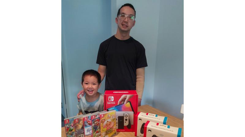 RAAF officer Flight Lieutenant Nathan Nguyen and his son with the care package from Veteran Gaming Australia.