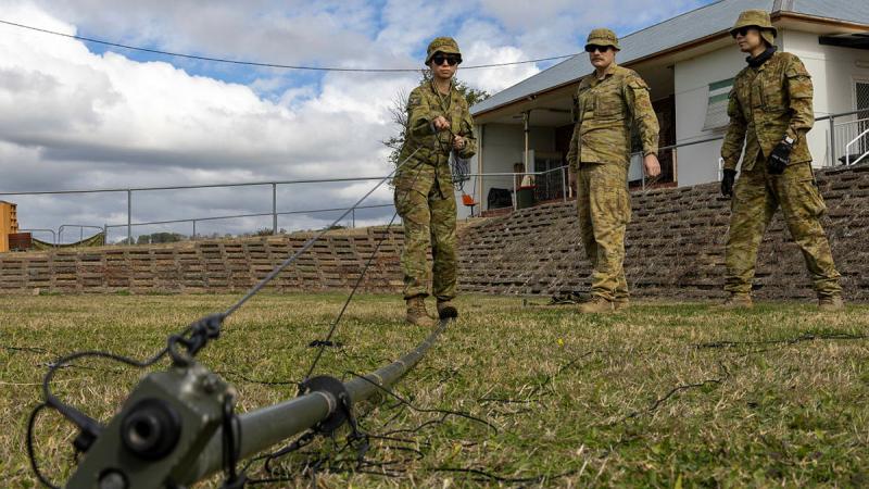 Private Chen Shi raises a communications mast off the ground during Exercise Arras Sprint.