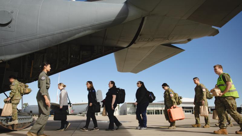 ADF personnel assist Australian and other tourists to board an Air Force C-130J Hercules in preparation to depart New Caledonia.