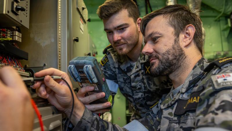 Navy soldiers inspect a component following a damage control scenario aboard HMAS Adelaide. Photo: Corporal Jacob Joseph