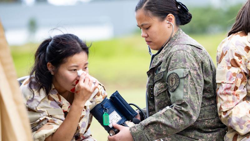 Philippine Air Force Captain Carissa Punsalan, an aviation medical examiner (right), provides medical care to a simulated casualty during an operational health support course at RAAF Base Amberley, Queensland.