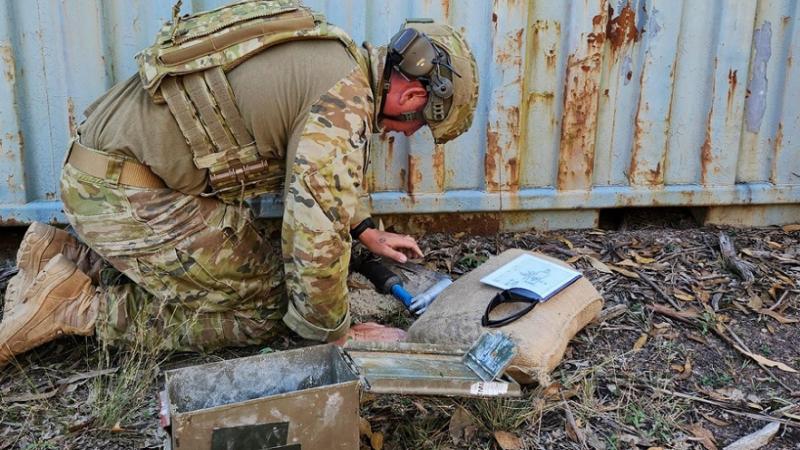An Air Force student measures the placement of his explosive ordnance disposal tool next to an unexploded sub munition during realistic training with the Defence Explosive Ordnance Training School, in Penrith.