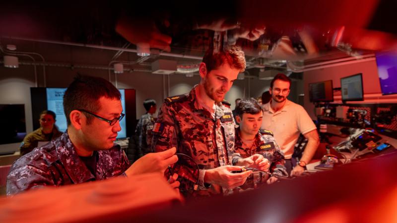 Personnel from the Royal Australian Navy, Japan Maritime Self Defence Force inspect hardware components during Exercise Blue Spectrum, at the Fleet Cyber Unit, Sydney. *This image has been digitally altered*