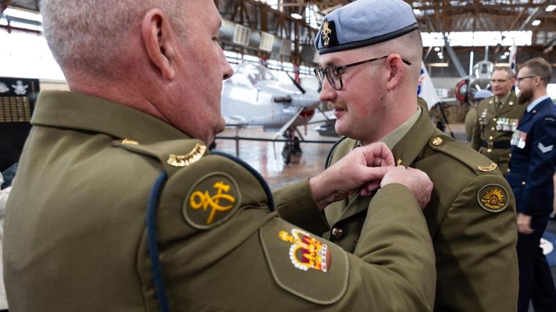 Warrant Officer Class Two Wayne Robinson pins is son's new collar dogs to his uniform at Craftsman Robinson's graduation as an Aircraft Technician, RAAF Wagga Wagga.