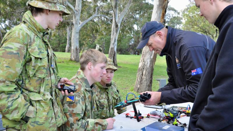 Flight Sergeant Justin Galbraith from the Royal Australian Air Force Drone Racing Team helps Australian Army Cadets fix their drones.