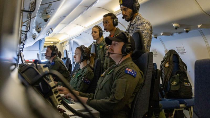 Malaysian obeservers monitor the P-8A Poseidon crew operating at their workstations during Operation Gateway.
