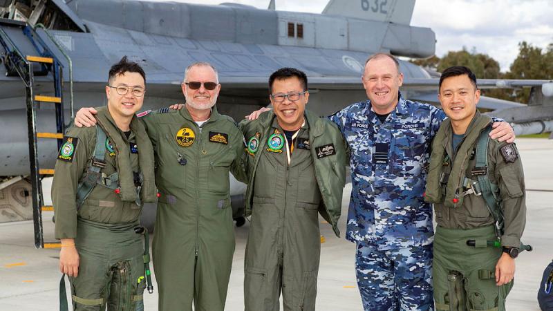 Wing Commander Greg Porche (second from right) and Republic of Singapore Air Force's detachment Group Commander Colonel Jonavan Ang (center) with members of both air forces and in front of an F-16D+ aircraft.