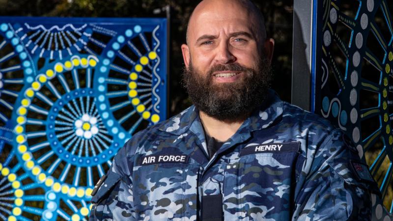 Royal Australian Air Force Flight Lieutenant Coen Henry, an Indigenous Liaison Officer at RAAF Base Williamtown, stands at the Yarning Circle, which is painted in a colour scheme representing the local Worimi people.