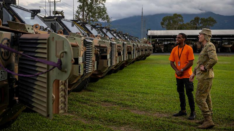 A soldier from 12th/16th Hunter River Lancers talks to a potential 51st Battalion, Far North Queensland Regiment, Indigenous recruit about the Bushmaster protected mobility vehicle at Porton Barracks in Cairns. 