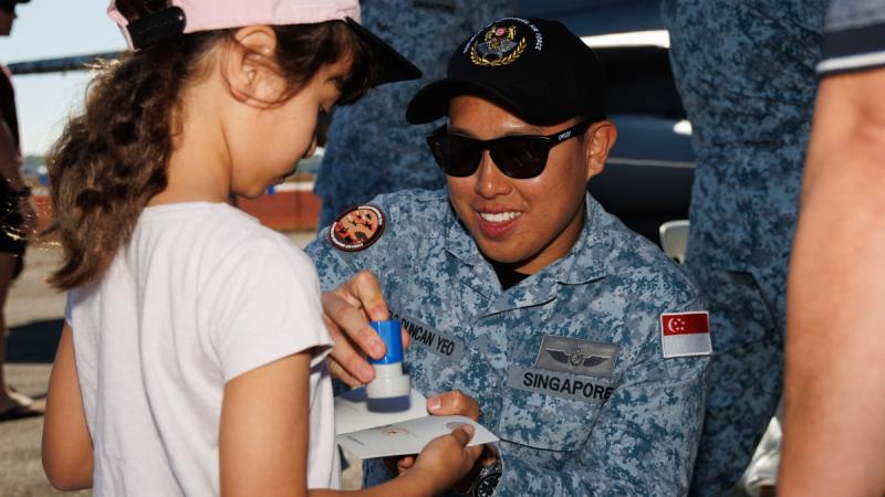 Republic of Singapore Air Force Flight Line Crew Military Expert 1-2 Duncan Yeo stamps Rachel's passport at the RAAF Darwin Open Day during Exercise Pitch Black 24. Photos: Leading Aircraftsman Kurt Lewis. 