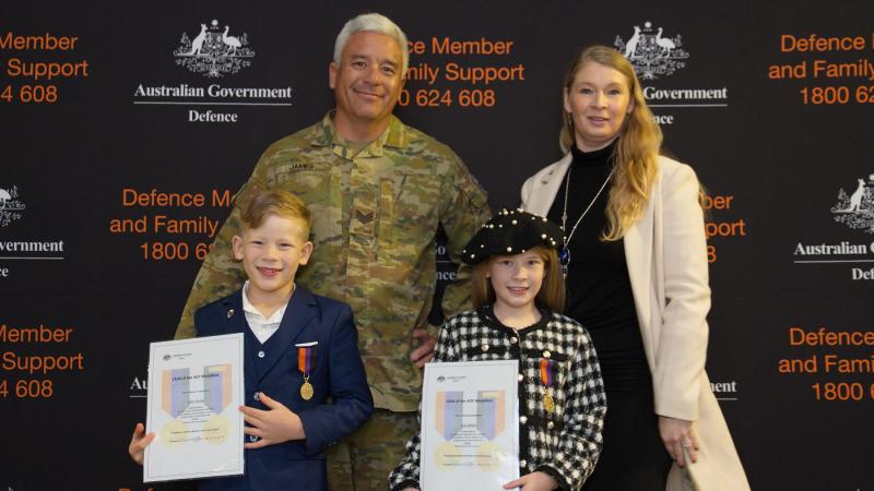 Parents, Sergeant Kim and Mrs Clare James with their kids, displaying their Child of ADF Medallions and certificates. 