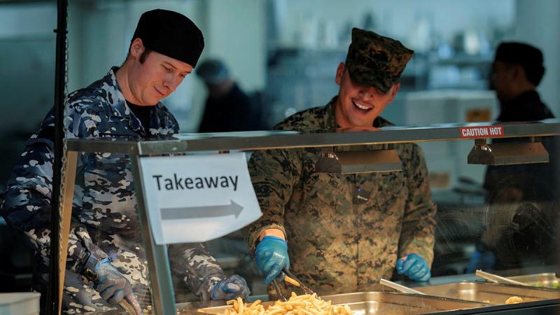 Royal Australian Air Force Chef Corporal Morgan Tuckey (left) and United States Marine Corps Chef Corporal Brandon Melgar serve lunch at the Junior Aviator's Mess during Exercise Pitch Black.