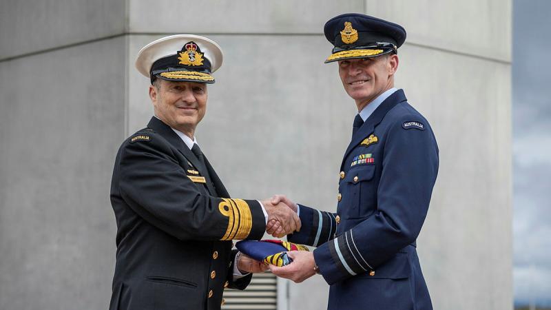 Vice Admiral David Johnston, left, hands the flag to Air Marshal Robert Chipman.
