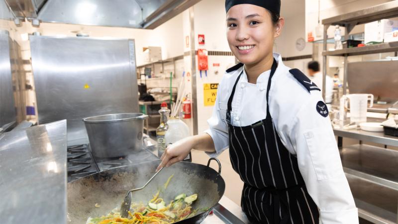 Leading Aircraftwoman Po-Yu Chen, a chef from 23 Squadron prepares a vegetable, noodle stir fry at RAAF Base Amberley.